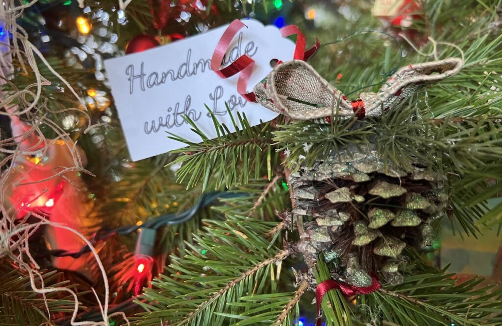 Photo of a handmade ornament on a Christmas tree with an attached tag reading "Handmade with Love"