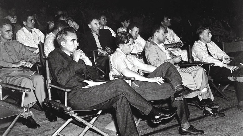 A group of physicists at a 1946 Los Alamos colloquium. Front row, left to right: Norris Bradbury, John Manley, Enrico Fermi, J.M.B. Kellogg. Second row, left to right: Colonel Oliver G. Haywood, unknown, J. Robert Oppenheimer, Richard Feynman, Phil B. Porter. Third row, left to right: Edward Teller, Gregory Breit, Arthur Hemmendinger Arthur Schelberg.