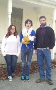 Left to right: Jassana, Jake, and Mike reunite in front of the Scattergood Friends meetinghouse for a photo with a reluctant chicken in December 2015.