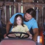 The author with child driving a tractor.