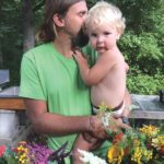 The author holding a child among flowers.