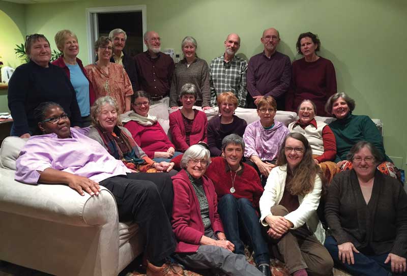 Two dozen people sitting in a living room.