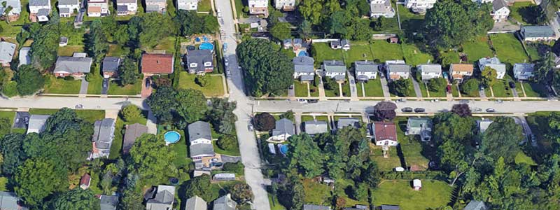 Overhead view of a city neighborhood with trees and yards.